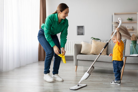 Mother and Child Cleaning Together in a Bright Living Room During Daytimeの写真素材