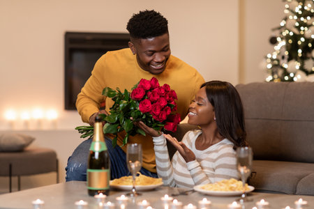African Man Gives Flowers to Girlfriend During Romantic Valentines Day Celebration at Homeの写真素材