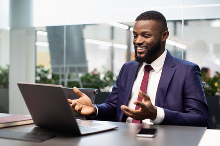 Happy black businessman having video chat, using laptopの写真素材