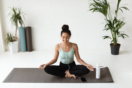Relaxed Young Woman Meditates While Listening to Music in a Modern Yoga Studioの写真素材