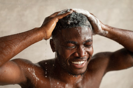 Black Man Washing Hair With Shampoo in Modern Bathroom During Showerの写真素材