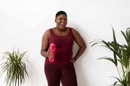 Joyful Plus Size African American Lady Enjoying Hydration in Home Sportswear