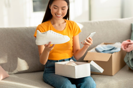 Positive Woman Unpacks New Sports Shoes and Shares Feedback on Online Shopping Experienceの写真素材