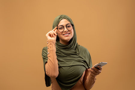Happy Arab Woman in Glasses Enjoying Online Learning on Smartphone in Studioの写真素材