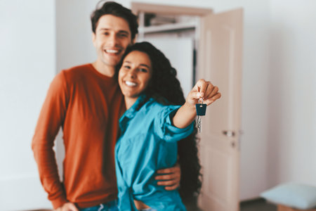 Happy Couple Holding Keys to Their New Home in Bright, Modern Interior Spaceの写真素材