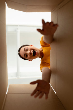 Happy Woman Unboxing Delivery in Her Home, Excited to See New Items Inside Carton Boxの写真素材