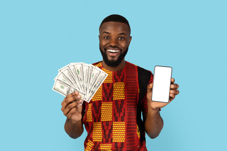 Cheerful Black Male Wearing Traditional African Costume Holding Blank Smartphone And Cashの写真素材