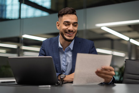 Happy Middle Eastern CEO Reviews Marketing Report in Modern Office Settingの写真素材