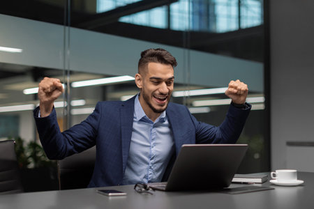 Emotional Arabic Businessman Celebrates Success at Modern Office After Closing a Dealの写真素材