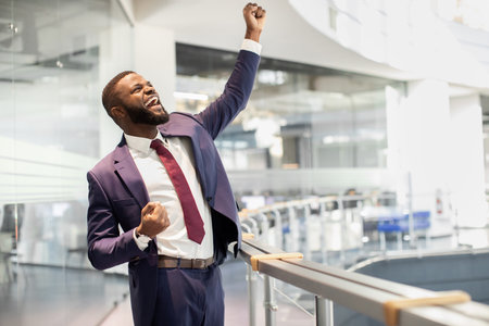 Cheerful african american young businessman celebrating successの写真素材