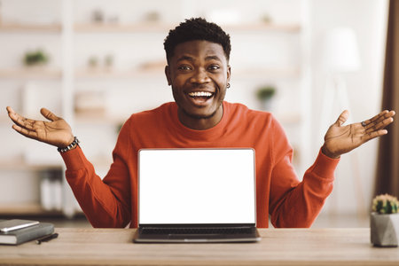Man Smiling and Gesturing in Front of a Laptop in a Cozy Indoor Space During Daytimeの写真素材