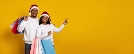 Young Couple Enjoying Holiday Shopping With Colorful Bags and Santa Hats on a Yellow Backgroundの写真素材