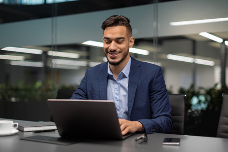Smiling Middle Eastern Businessman Working on Computer in Modern Office Environment