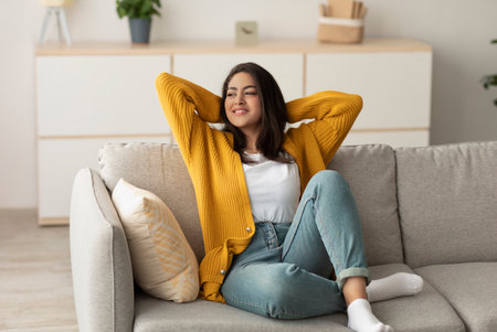 Serene Arab Woman Relaxing on a Minimalist Sofa Enjoying Peaceful Solitude at Homeの写真素材