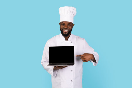Cooking Website. Smiling Black Chef Pointing At Blank Laptop In His Handの写真素材