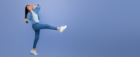 Joyful Woman Dancing With One Leg Raised Against a Blue Backgroundの写真素材
