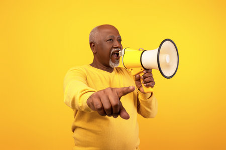 Cheerful Senior Man Shares Big Announcement With Megaphone on Orange Backgroundの写真素材