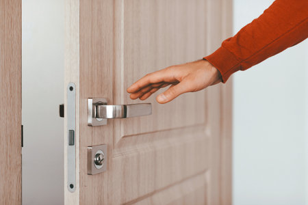 Hand Reaching for Metal Door Handle in Modern Interior Settingの写真素材