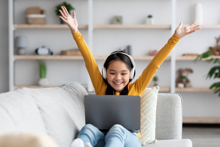 Happy Girl Celebrating While Using a Laptop at Home During Daytime in a Cozy Living Room
