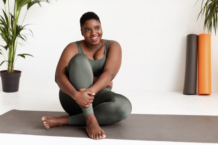 Positive Plus Size Lady Enjoying Yoga Session on Fitness Mat in Bright Studio Space