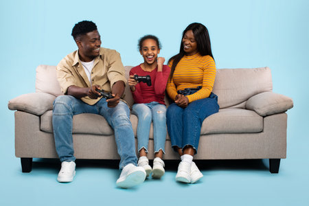 Father and Daughter Enjoy Playful Gaming Time With Mother Cheering on Blue Background