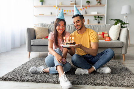 Couple Celebrating a Birthday With Cake, Candles, and Party Hats Indoorsの写真素材