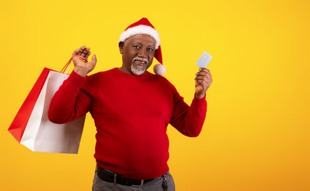 Christmas Shopping With a Joyful Senior Man Holding Bags and a Credit Card in Festive Attireの写真素材