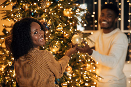 Happy Millennial Couple Joyfully Decorating a Christmas Tree at Home for the Holidaysの写真素材