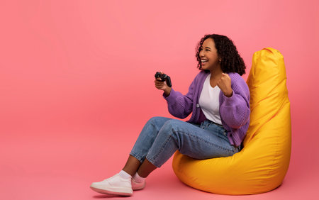 Excited Young Woman Celebrates Victory in Video Game Competition From Her Cozy Bean Bag Chairの写真素材