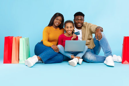 Happy Black Family Shopping Online Together With a Laptop and Credit Card at Homeの写真素材
