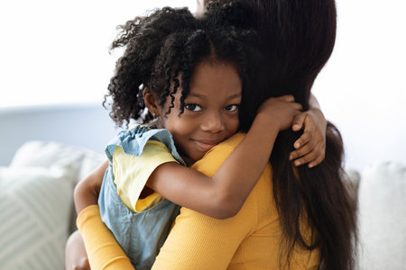 Loving Hug Between a Mother and Daughter in a Cozy Living Room During Daytimeの写真素材