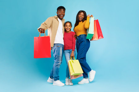 Family Enjoys Shopping Together With Colorful Bags Against a Bright Blue Backgroundの写真素材