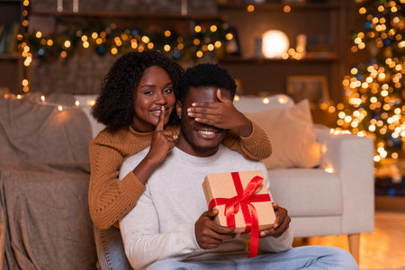 Surprise Gift Exchange by Smiling Couple Near Decorated Christmas Tree at Homeの写真素材