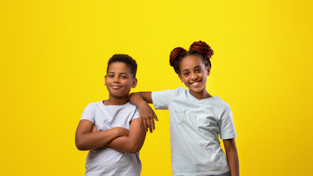 Happy Kids Posing Together Against a Vibrant Yellow Background in a Joyful Settingの写真素材
