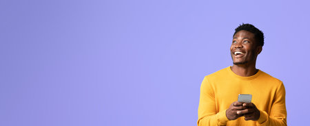 Smiling Man Engaged With Smartphone in Front of a Colorful Purple Backgroundの写真素材