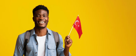 Young Man Waving Turkish Flag Against Bright Yellow Background in Joyful Momentの写真素材