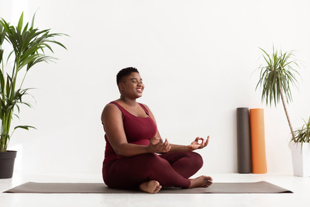 Positive Black Lady Practicing Yoga and Meditation in a Peaceful Center Environmentの写真素材