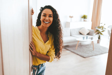 Smiling Woman Greets Visitors at Home Entrance During Bright and Sunny Dayの写真素材