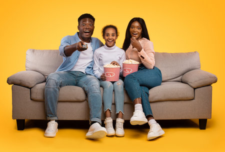 Overjoyed Family Enjoys Movie Night With Popcorn on a Cozy Couchの写真素材