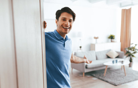 Smiling Man Stands in Doorway of Cozy Living Room Atmosphere Inviting Guests Insideの写真素材