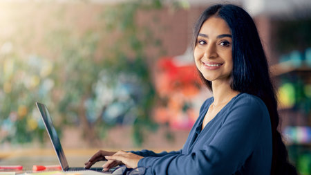 Woman Working on Laptop in a Bright and Vibrant Workspaceの写真素材