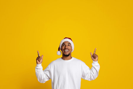 Happy Man in Santa Hat Celebrating Christmas With Bright Yellow Backgroundの写真素材
