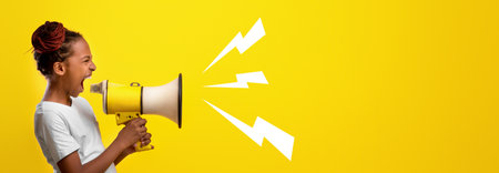 Child Loudly Expresses Excitement With Megaphone Against Bright Yellow Backdropの写真素材