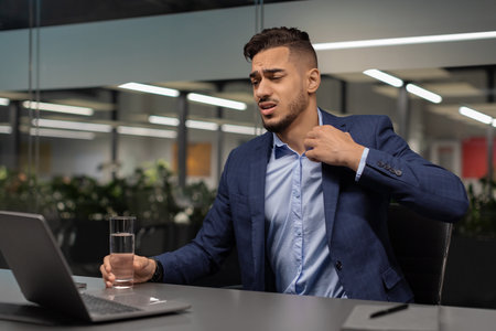 Distressed Businessman Managing Stress in Modern Office During Financial Crisisの写真素材
