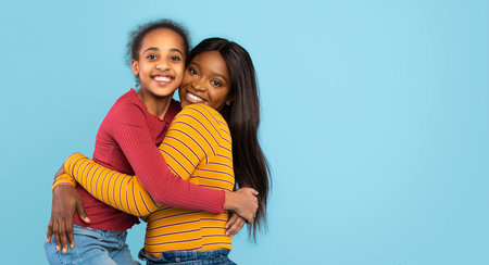 Strong Bond Between Daughter and Mother Expresses Love and Happiness in a Bright Blue Settingの写真素材