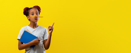Child With Pencil in Mouth Making a Thoughtful Gesture Against a Bright Yellow Backgroundの写真素材