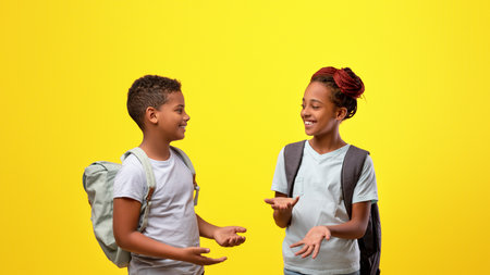 Two Children Happily Chatting in Front of a Bright Yellow Backgroundの写真素材