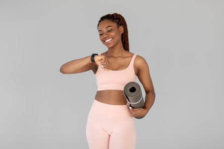Confident Athletic Woman Checking Smartwatch While Holding Fitness Mat in Modern Sports Outfit
