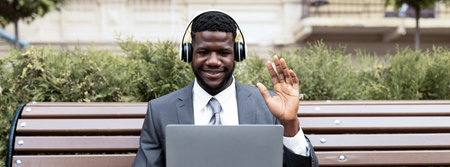 Businessman Enjoys a Video Call Outdoors While Sitting on a Benchの写真素材