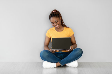 Young Black Woman Showing Laptop With Empty Screen, Perfect for Website Mockupの写真素材